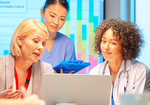 A group of doctors gathered around a desk looking at a computer screen.