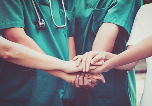 A nurse's hands holding a tiny red crochet heart