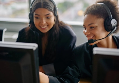 Two healthcare support professionals wearing headsets and working on computers