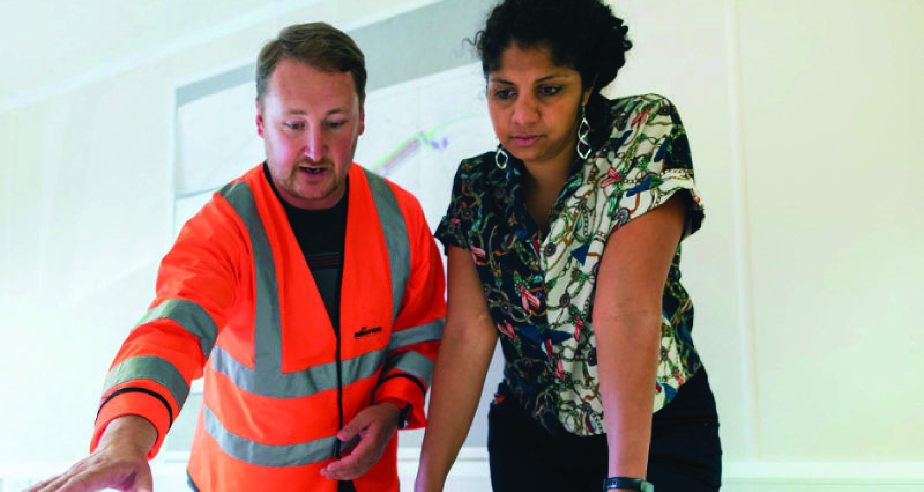 Two employees standing over a table discussing work.