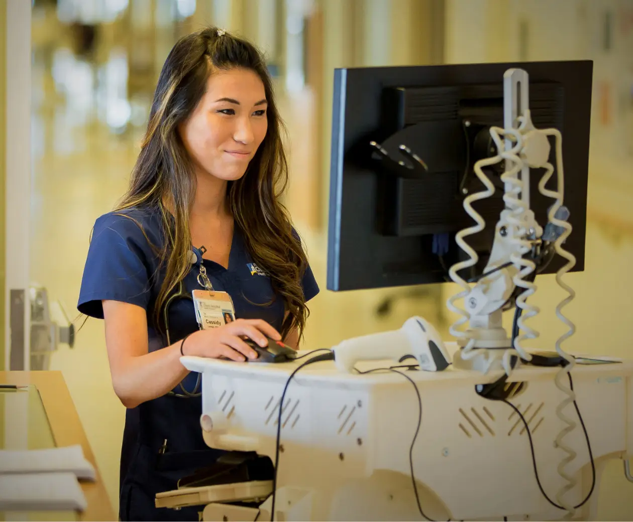 A Christ Hospital Health Network nurse smiling as she works on a portable computer.